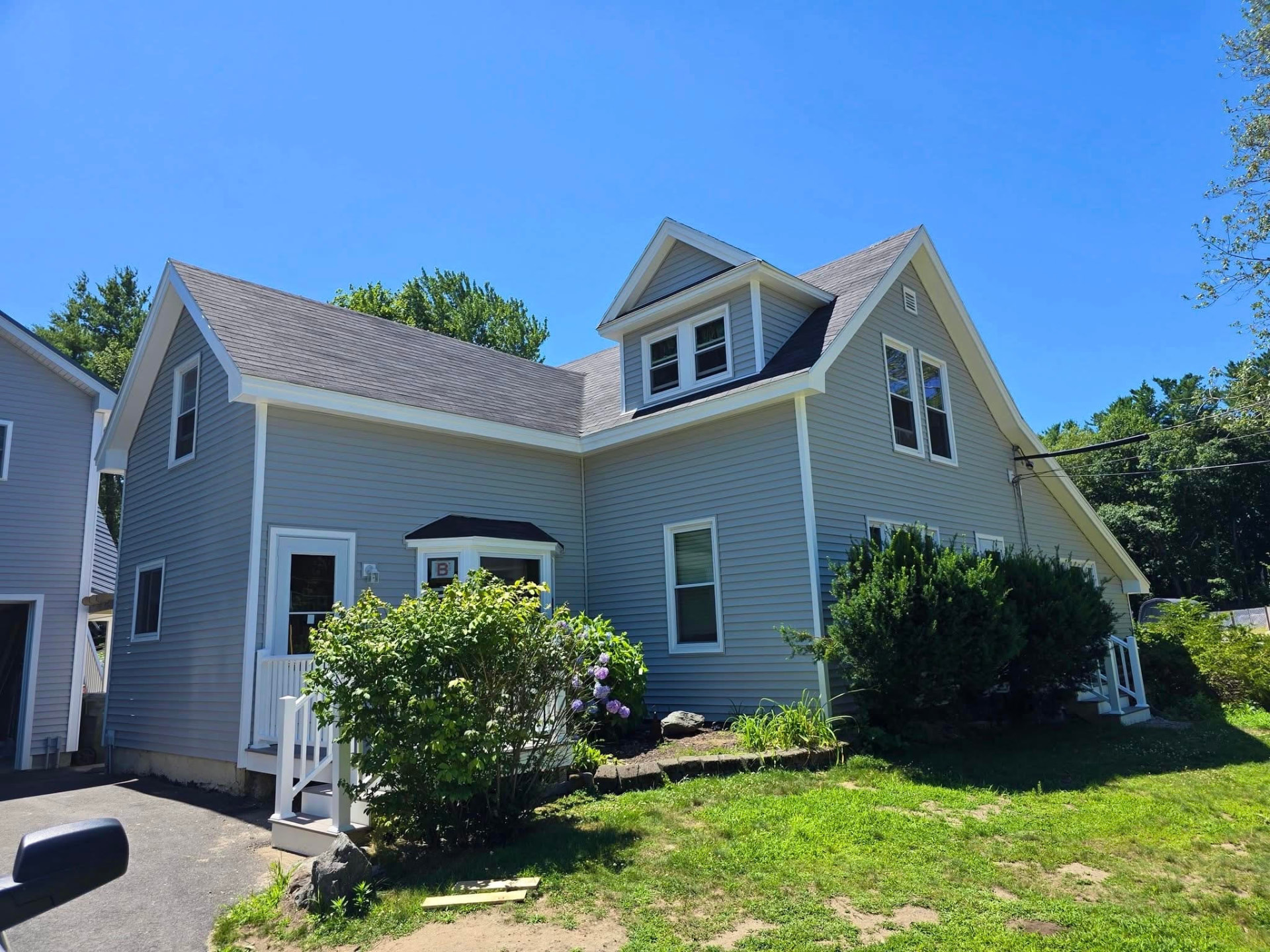 Renovated gray-sided home with new roof, dormer and white trim